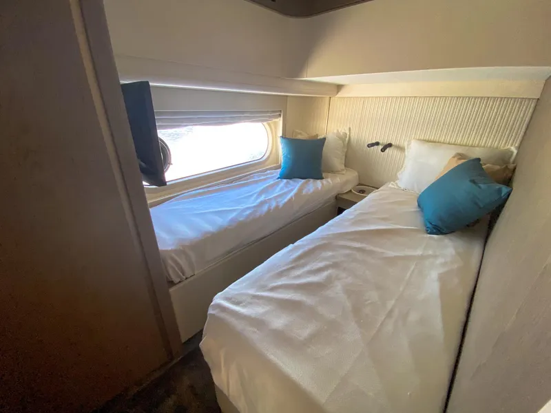 Slide: The Image of Twin cabin in 2025 Azimut Magellano 60 yacht, featuring cozy beds and a window view. - 15