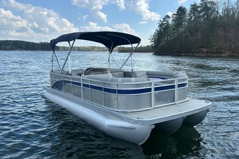Slide: The Image of 2023 Bennington 22 SSR pontoon boat on a serene lake with lush forest backdrop. - 3