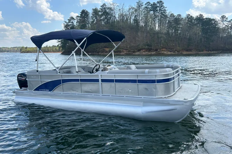 Slide: The Image of 2023 Bennington 22 SSR pontoon boat on a scenic lake with forested shoreline. - 4