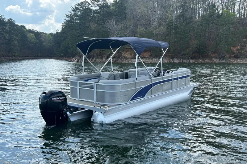 Slide: The Image of 2023 Bennington 22 SSR pontoon boat on a scenic lake with forested shoreline. - 6