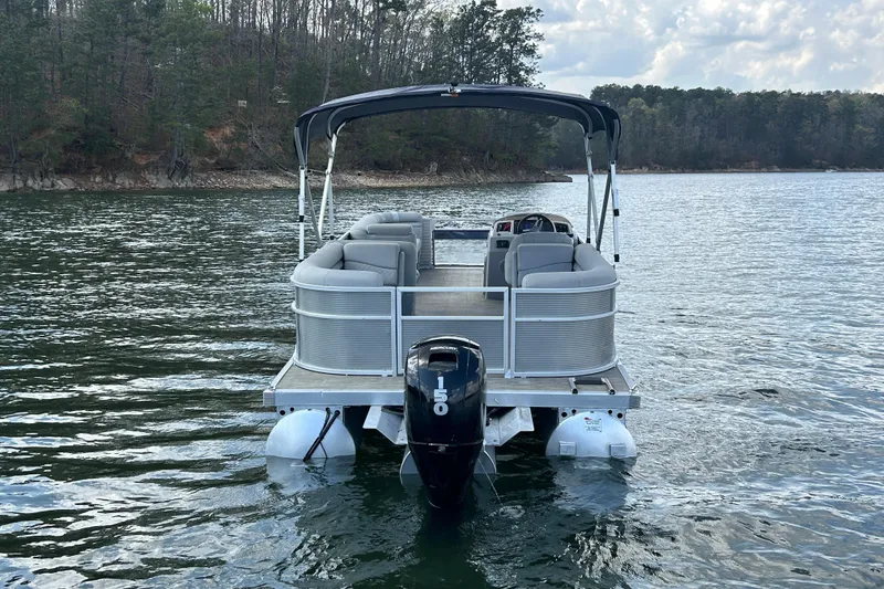 Slide: The Image of 2023 Bennington 22 SSR pontoon boat on a serene lake with forested shoreline. - 7