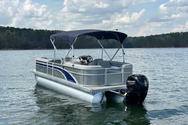 Slide: The Image of 2023 Bennington 22 SSR pontoon boat on a serene lake with a Mercury outboard motor. - 8