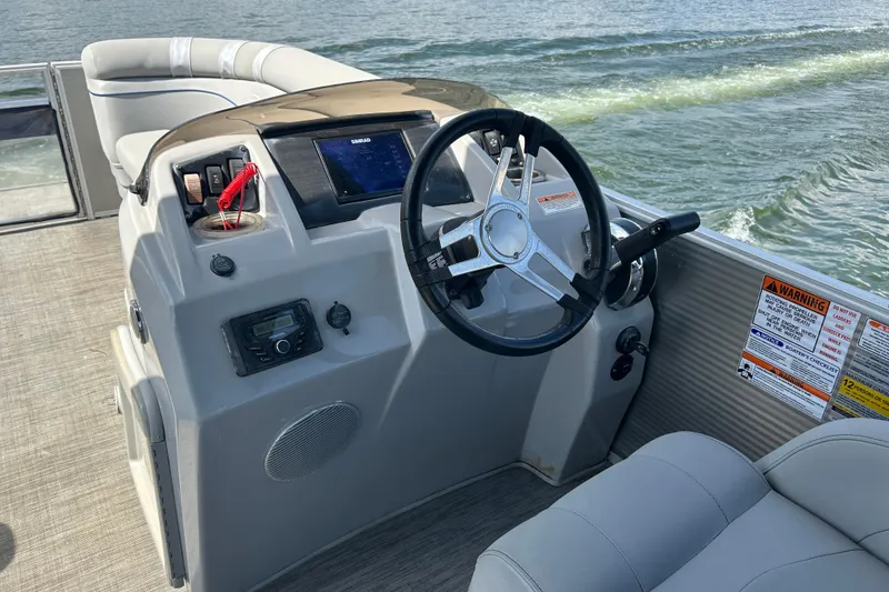 Slide: The Image of 2023 Bennington 22 SSR boat dashboard with steering wheel and controls on water. - 9