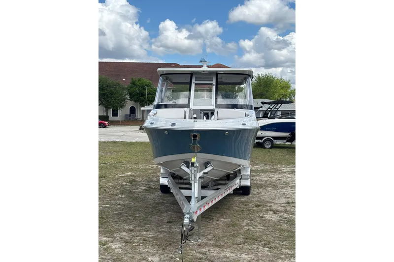 Slide: The Image of 2026 Crownline 280 DC boat on trailer, parked outdoors under a cloudy sky. - 2