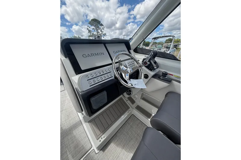 Slide: The Image of 2026 Crownline 280 DC helm with Garmin displays and modern controls under a cloudy sky. - 22