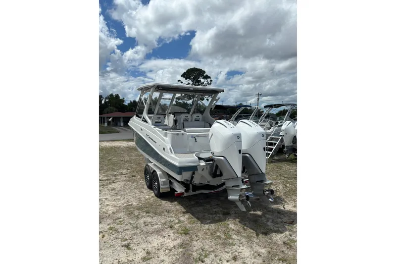 Slide: The Image of 2026 Crownline 280 DC boat with dual outboard motors, parked on a trailer under cloudy skies. - 3