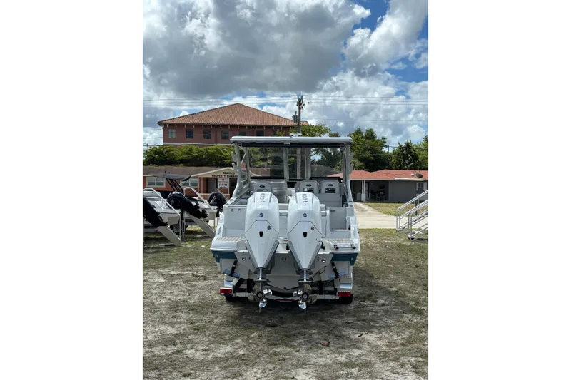 Slide: The Image of 2026 Crownline 280 DC boat with dual outboard motors, parked outdoors under cloudy sky. - 7