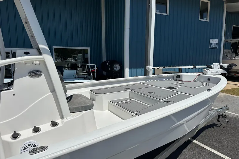 Slide: The Image of 2024 Avid 23 Mag boat with sleek design, docked near blue building. - 2