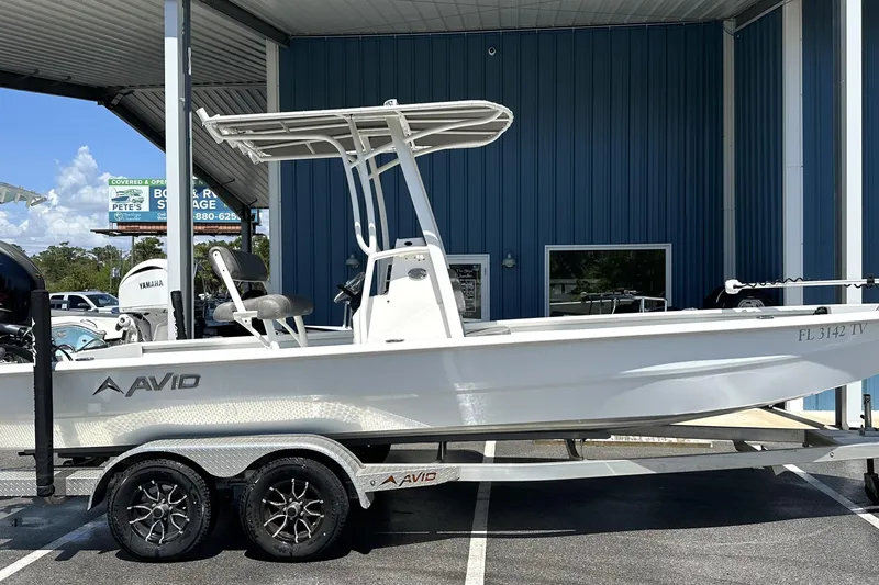 Slide: The Image of 2024 Avid 23 Mag boat on trailer, parked under a blue metal canopy. - 9