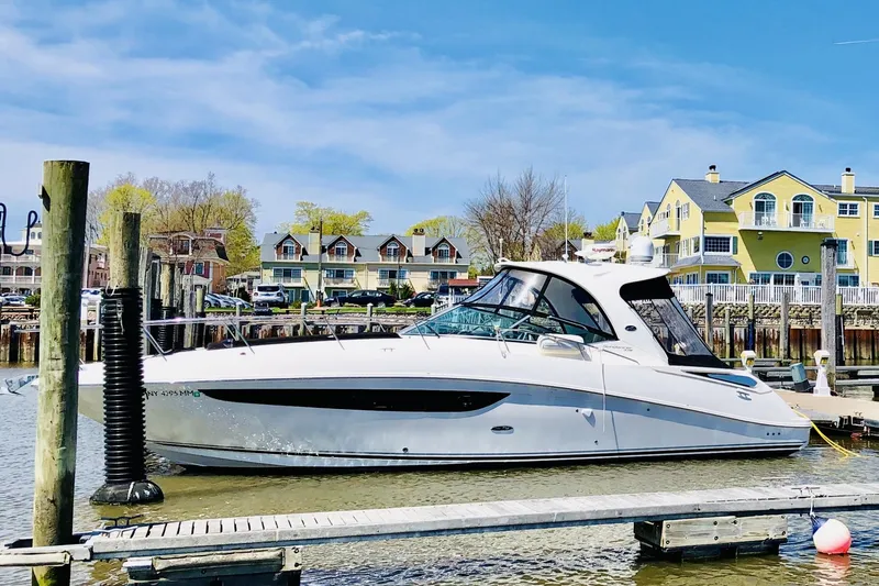 Slide: The Image of 2017 Sea Ray Sundancer 370 docked at a marina with waterfront homes in the background. - 2