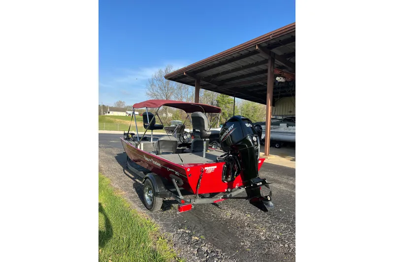 Slide: The Image of 2023 Tracker Bass Tracker Classic XL boat with canopy and outboard motor in a sunny setting. - 3