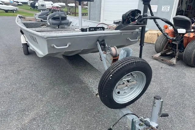 Slide: The Image of 1980 Lowe Big Jon 16 boat on trailer, parked outdoors near other boats and equipment. - 4