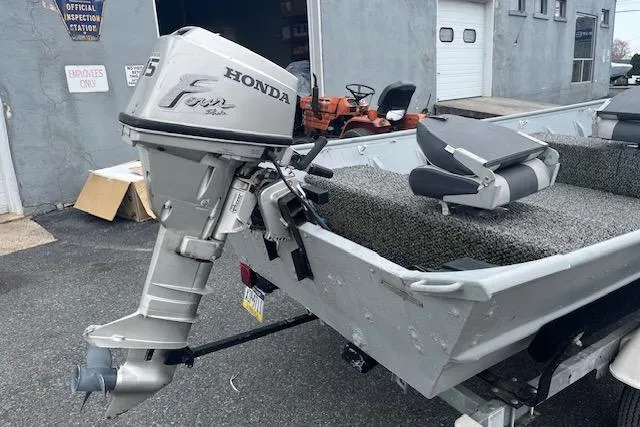 Slide: The Image of 1980 Lowe Big Jon 16 boat with Honda outboard motor, parked near a building. - 7