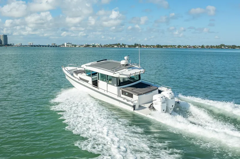 The Image of 2017 Axopar 37 XC Cross Cabin cruising on open water, city skyline in background. - 0