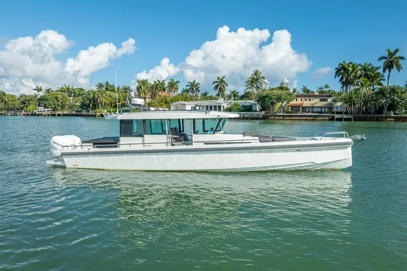 Slide: The Image of 2017 Axopar 37 XC Cross Cabin boat on calm water, surrounded by palm trees. - 2