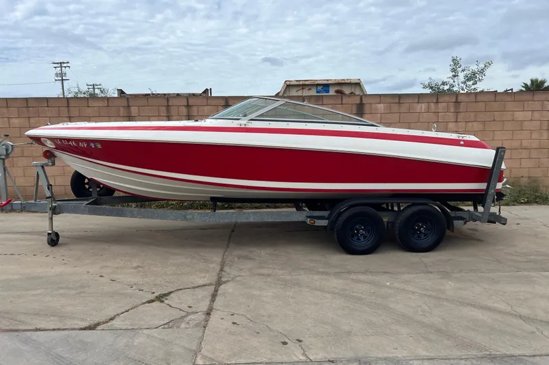 Slide: The Image of Red 1996 Cobalt 220 boat on trailer, parked outdoors against brick wall. - 1