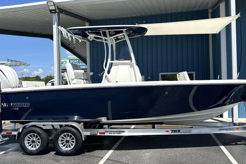 Slide: The Image of 2026 Pathfinder 2400 TRS boat on trailer, parked under a metal canopy. - 1