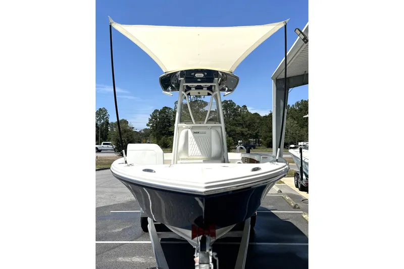 Slide: The Image of 2026 Pathfinder 2400 TRS boat with canopy, parked outdoors under clear blue sky. - 6