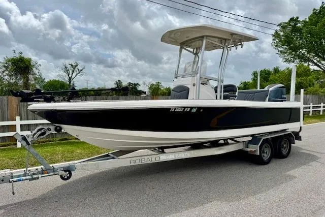 The Image of 2015 Robalo 226 Cayman boat on trailer, parked on a suburban street. - 1