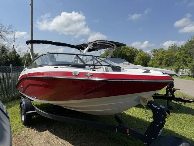 Slide: The Image of 2025 Yamaha SX195 boat, red and white, parked on trailer outdoors. - 2