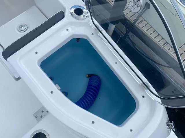 Slide: The Image of Yamaha Boats 2024 255 FSH Sport H storage compartment with blue hose. - 8