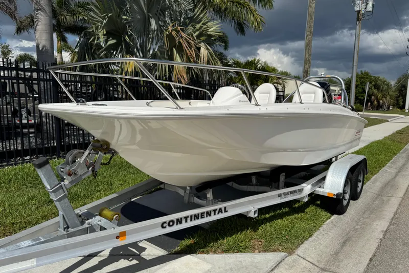 Slide: The Image of 2017 Boston Whaler 170 Super Sport boat on trailer, parked near palm trees. - 12