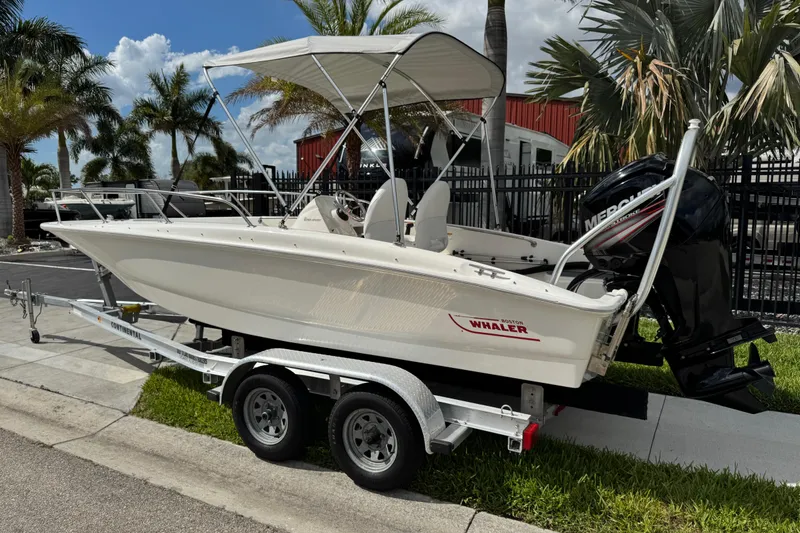 Slide: The Image of 2017 Boston Whaler 170 Super Sport boat on trailer, parked near palm trees. - 22