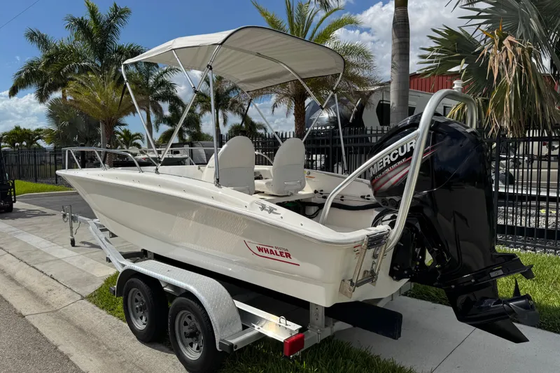 Slide: The Image of 2017 Boston Whaler 170 Super Sport boat on trailer, featuring Mercury engine, parked outdoors. - 23