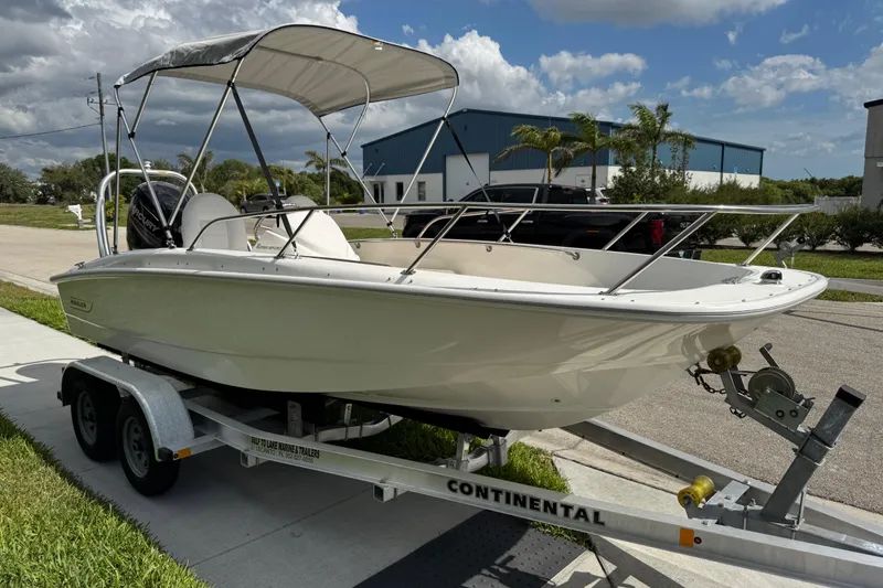 Slide: The Image of 2017 Boston Whaler 170 Super Sport boat on trailer, parked outdoors under cloudy sky. - 26