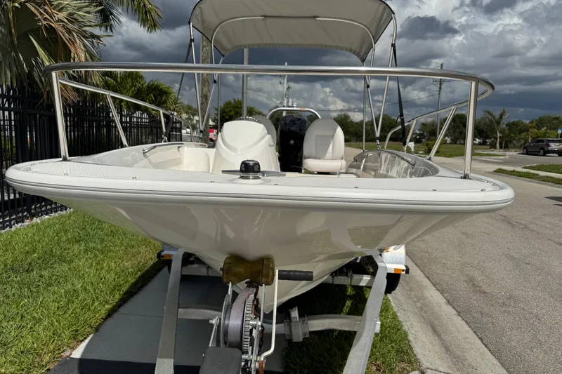 Slide: The Image of 2017 Boston Whaler 170 Super Sport boat on trailer, parked outdoors under cloudy sky. - 27