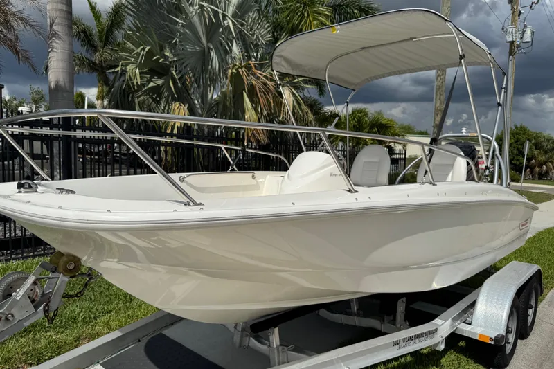 Slide: The Image of 2017 Boston Whaler 170 Super Sport boat with canopy on trailer, surrounded by palm trees. - 28