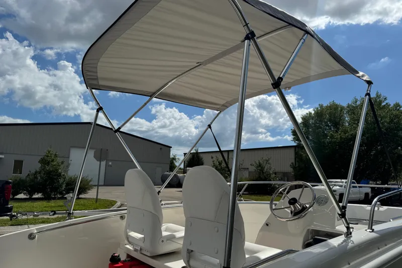 Slide: The Image of 2017 Boston Whaler 170 Super Sport boat with bimini top under a cloudy sky. - 31