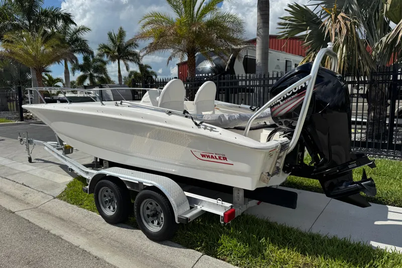 Slide: The Image of 2017 Boston Whaler 170 Super Sport boat on trailer, parked near palm trees. - 4