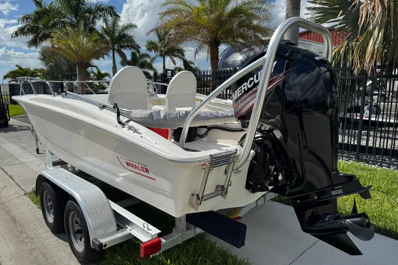Slide: The Image of 2017 Boston Whaler 170 Super Sport boat on trailer, with Mercury outboard motor, palm trees in background. - 5