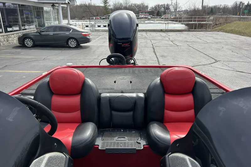 Slide: The Image of 2007 Skeeter 20i boat interior with red and black seating in a parking lot. - 17