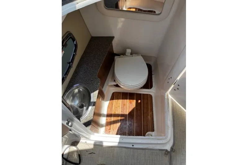 Slide: The Image of 2014 Chaparral 257 SSX boat bathroom with toilet, sink, and wooden flooring. - 28