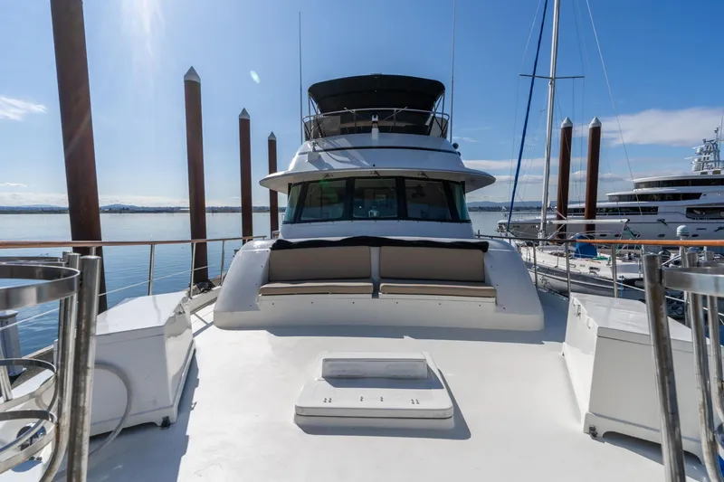 Slide: The Image of 1986 Hatteras 63 Motor Yacht docked, showcasing spacious deck and sleek design. - 100