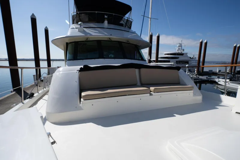 Slide: The Image of 1986 Hatteras 63 Motor Yacht with cushioned seating on deck, docked at marina. - 102