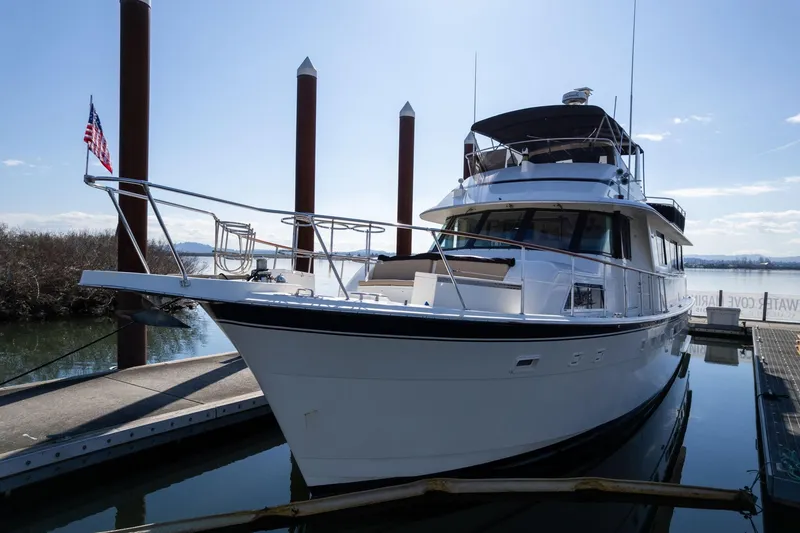 Slide: The Image of 1986 Hatteras 63 Motor Yacht docked at marina, clear sky, American flag visible. - 106