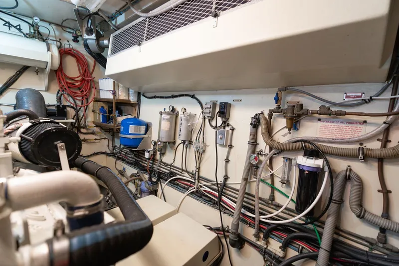 Slide: The Image of Engine room of a 1986 Hatteras 63 Motor Yacht, showcasing complex wiring and equipment. - 110
