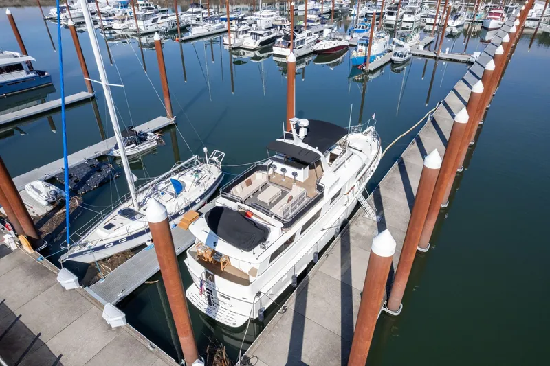 Slide: The Image of 1986 Hatteras 63 Motor Yacht docked at marina, surrounded by sailboats. - 143