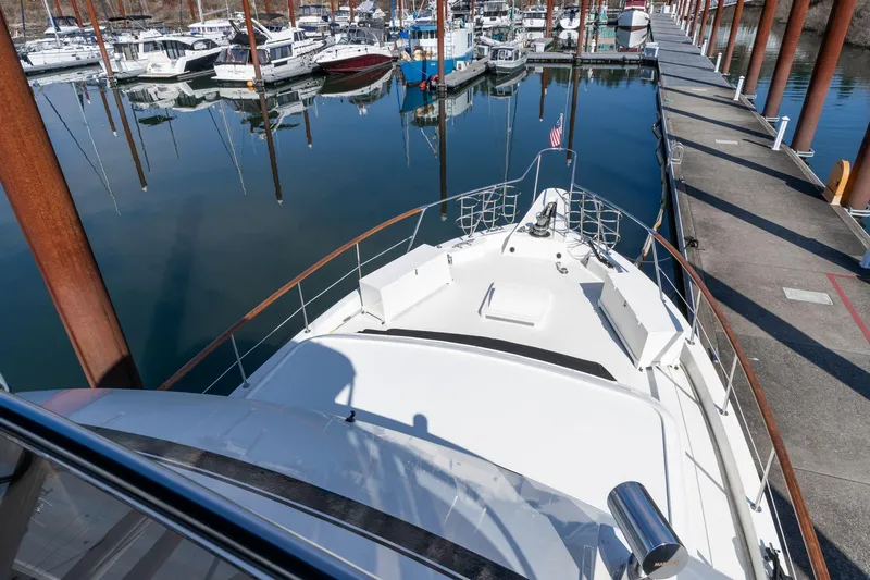 Slide: The Image of 1986 Hatteras 63 Motor Yacht docked at marina, showcasing sleek deck design. - 145