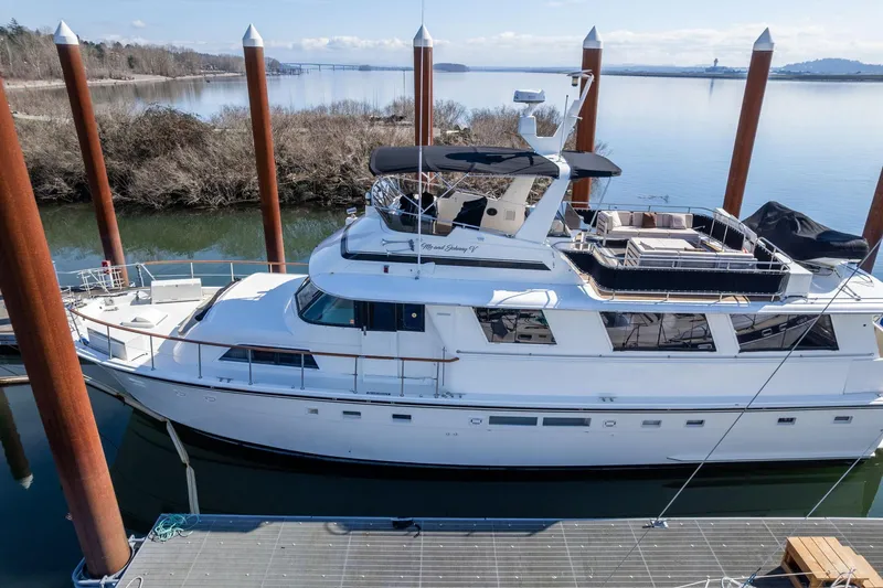 Slide: The Image of 1986 Hatteras 63 Motor Yacht docked by a serene waterfront. - 146