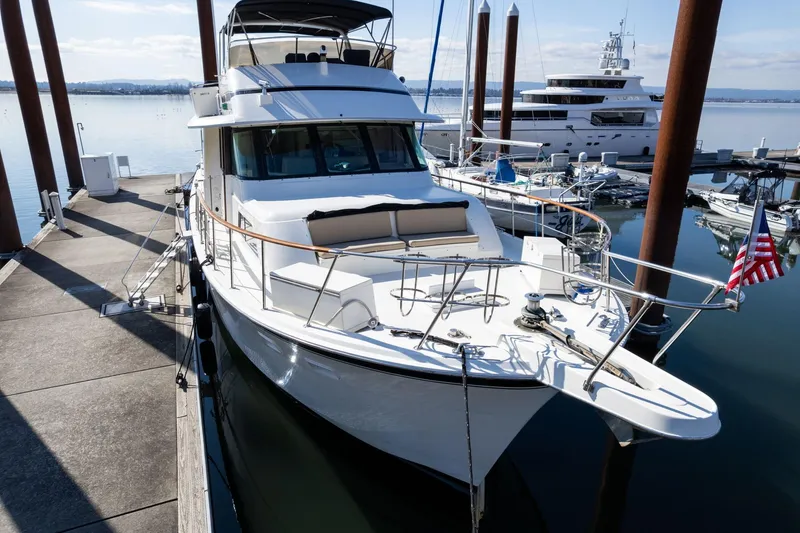 Slide: The Image of 1986 Hatteras 63 Motor Yacht docked at marina, featuring sleek design and American flag. - 149