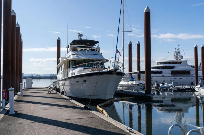 Slide: The Image of 1986 Hatteras 63 Motor Yacht docked at a marina under clear blue skies. - 153