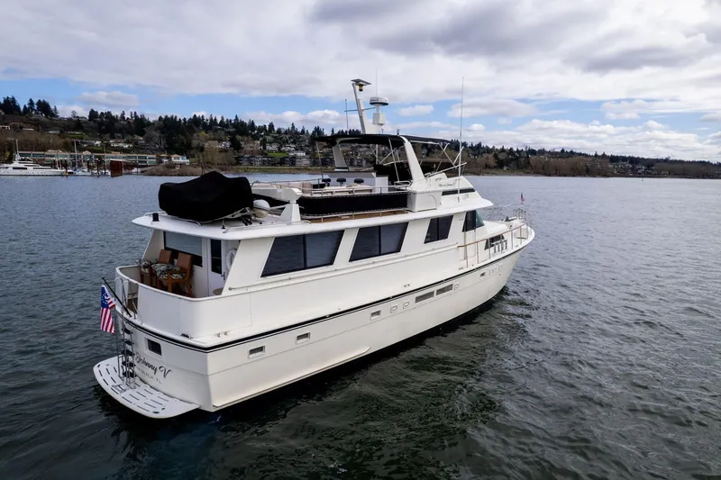 Slide: The Image of 1986 Hatteras 63 Motor Yacht cruising on a serene lake under a cloudy sky. - 154