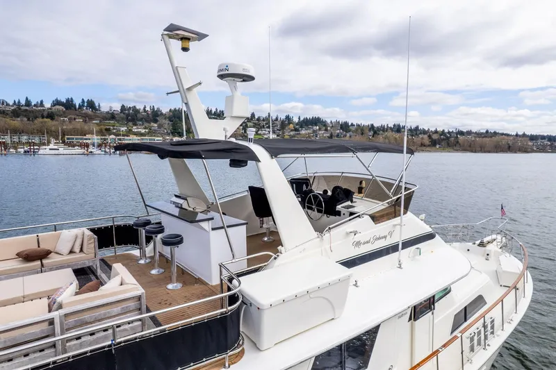 Slide: The Image of 1986 Hatteras 63 Motor Yacht on water, featuring spacious deck and seating area. - 155