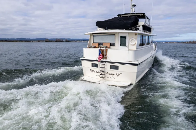 Slide: The Image of 1986 Hatteras 63 Motor Yacht cruising on open water with American flag. - 156