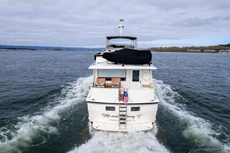 Slide: The Image of 1986 Hatteras 63 Motor Yacht cruising on open water, rear view with American flag. - 157