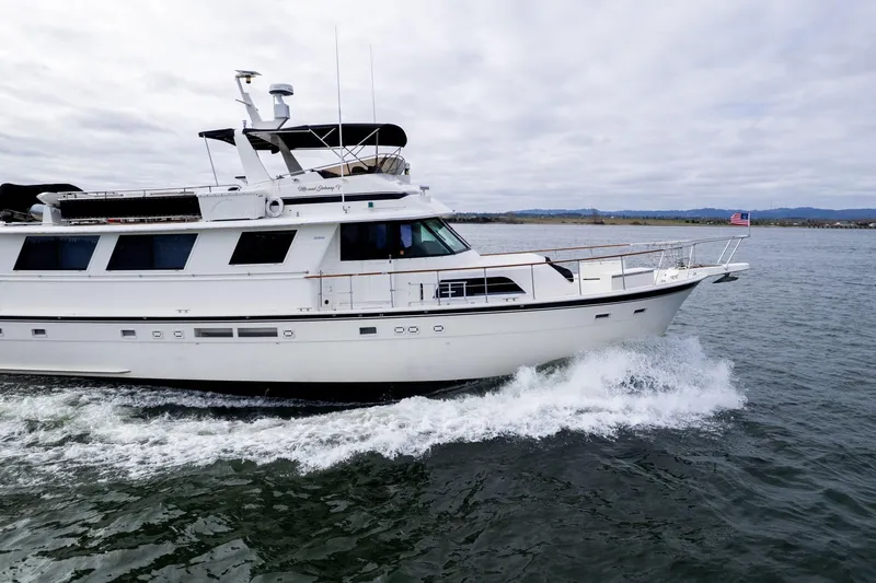 Slide: The Image of 1986 Hatteras 63 Motor Yacht cruising on open water under cloudy skies. - 158